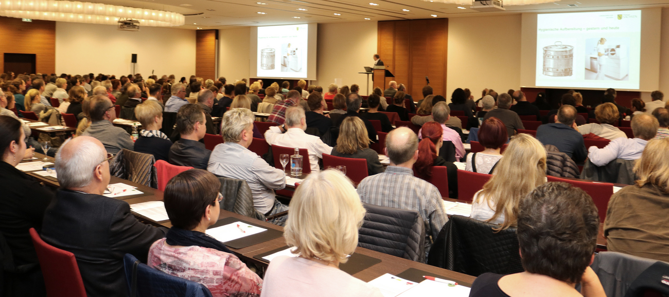 Viele Menschen hören und sehen in einem Saal eine Präsentation